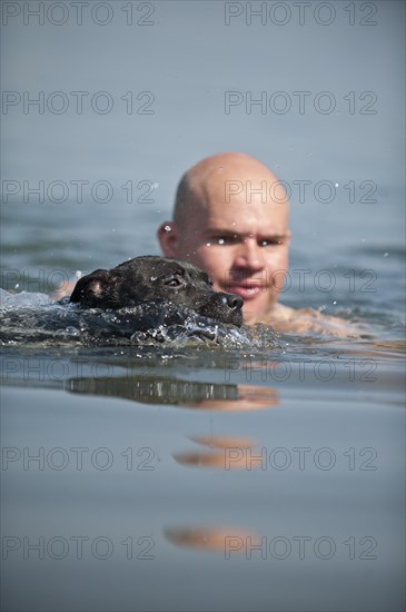A man and a dog swimming in a lake