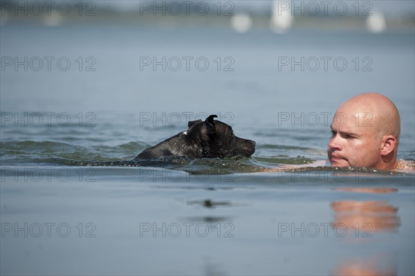 A man and a dog swimming in a lake