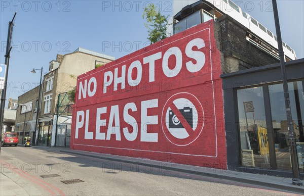 Graffiti 'No photos please' on a wall of the Village Underground building