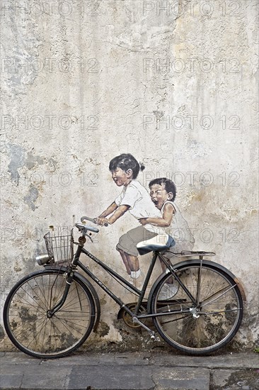 Bicycle in front of house wall with children painted as if they are riding the bike