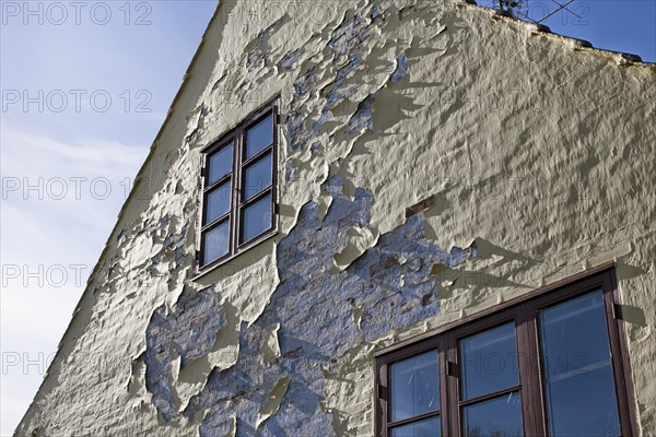 Facade of a house with flaking paint and rendering in need of restoration