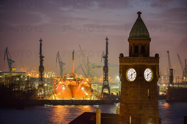 The Water Level Tower of the St. Pauli Landing Stages in front of the dry dock of the Blohm and Voss Shipyards with the ship Petrojarl Banff in the dock