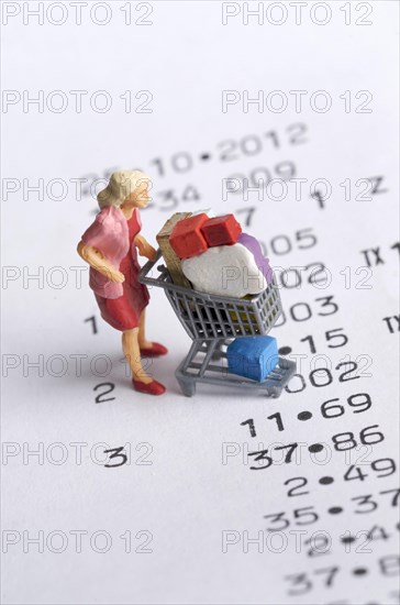 Miniature figurine of a woman with a shopping chart on a receipt