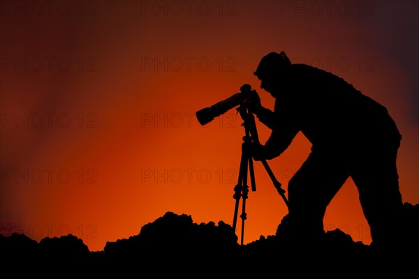 Photographer taking pictures at the lava lake in the crater of Mount Nyiragongo volcano