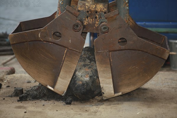 Bomb from the Second World War between the buckets of an excavator