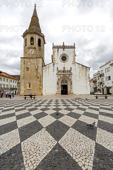 Church and bell tower of Sao Joao Baptista with a geometric paving pattern on the marketplace of Tomar