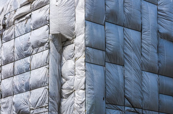 Scaffolding surrounded by a silver plastic tarp