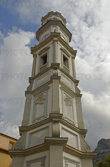 The white tower of the church of the small village Calenzana in front of a cloudy sky. Calenzana is in the western part of the mediterranean island Corsica