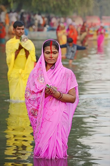 Man and a woman wearing a sari standing in water during the Hindu Chhath Festival