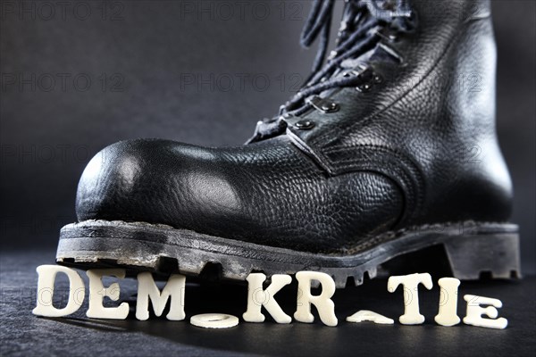 Combat boot standing on the word 'Demokratie'