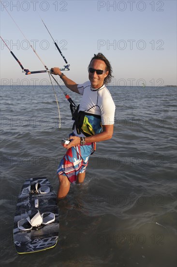 Kitesurfer standing in water with the kite