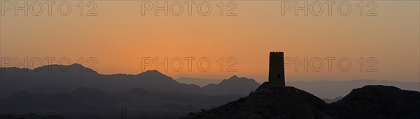 Sunrise over Al-Mudayrib with the silhouette of a lone watch tower