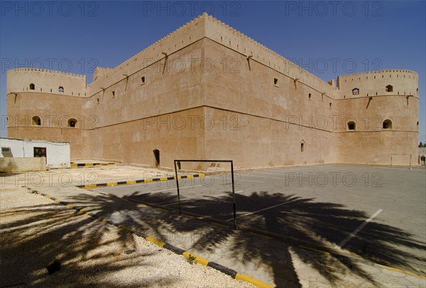 Al Hazm Castle behind the shadows of two palm trees