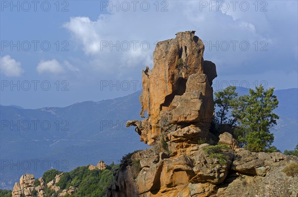 The typical bizarre red rocks of the Calanche of Piana below a blue sky and some clouds. The Calanche of Piana is in the western part of the island Corsica