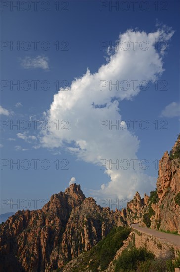 The typical bizarre red rocks of the Calanche of Piana below a blue sky and some clouds. The Calanche of Piana is in the western part of the island Corsica