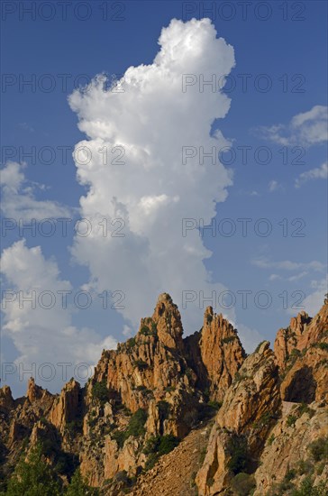 The typical bizarre red rocks of the Calanche of Piana below a blue sky and some clouds. The Calanche of Piana is in the western part of the island Corsica