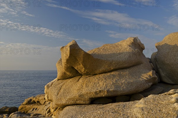 Bizarre granite rocks at the coast of the mediterranean sea in Calvi below a blue sky with some clouds. Calvi is in the department Haute-Corse