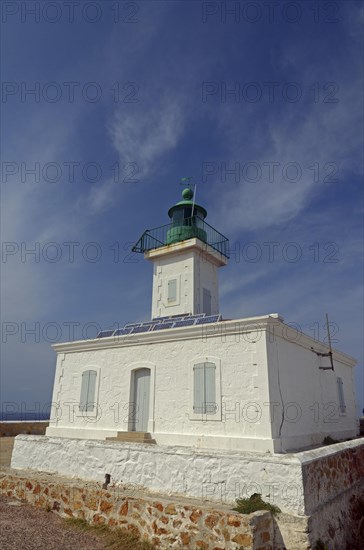 The white lighthouse on the island Ile de la Pietra near L'Ile-Rousse below a blue sky with some clouds. L'Ile-Rousse is in the department Haute-Corse