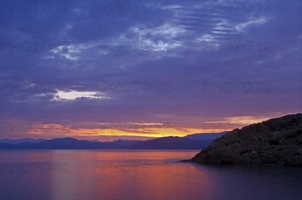 The rising sun forms sun beams behind the rocks of the island Ile de la Pietra near L'Ile-Rousse. L'Ile-Rousse is in the department Haute-Corse