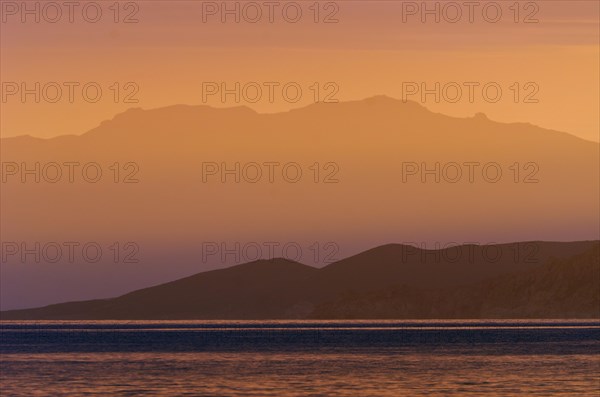 The rising sun forms sun beams behind the rocks of the island Ile de la Pietra near L'Ile-Rousse. L'Ile-Rousse is in the department Haute-Corse