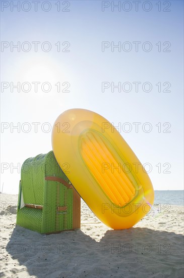 Colourful roofed wicker beach chair and a yellow inflatable boat