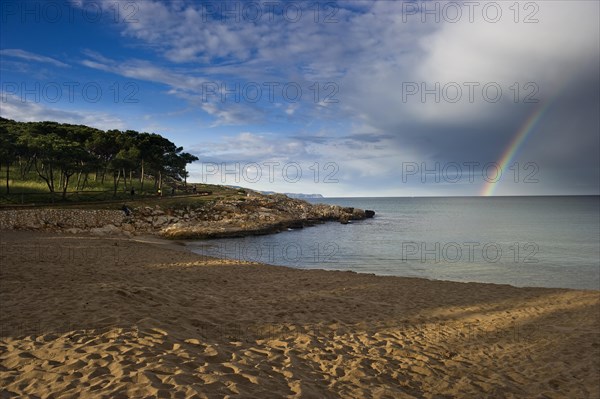 Sandy beach with rainbow over the sea