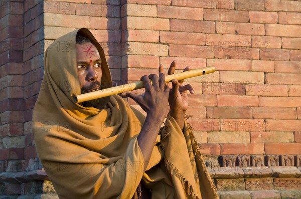 Young man playing flute at the burning ghats