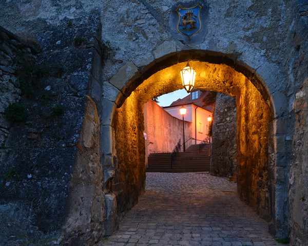 Lane passing underneath a stone archway at dusk