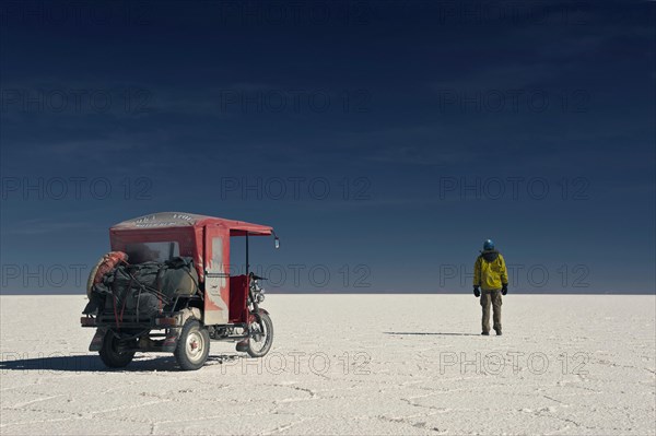 Man and a mototaxi on the dry salt lake of Salar de Uyuni