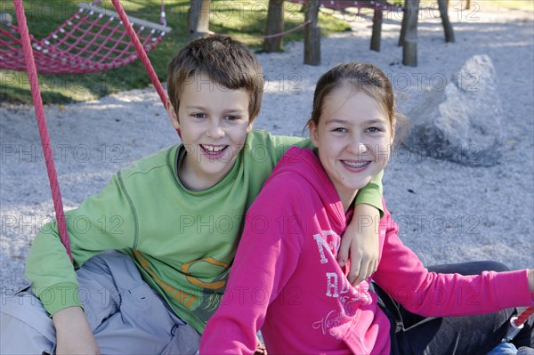 A boy and girl sitting on a playground