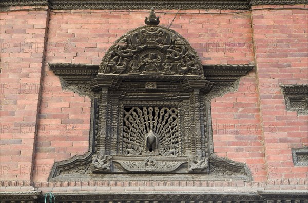 Ornate carved wooden window with a peacock sculpture