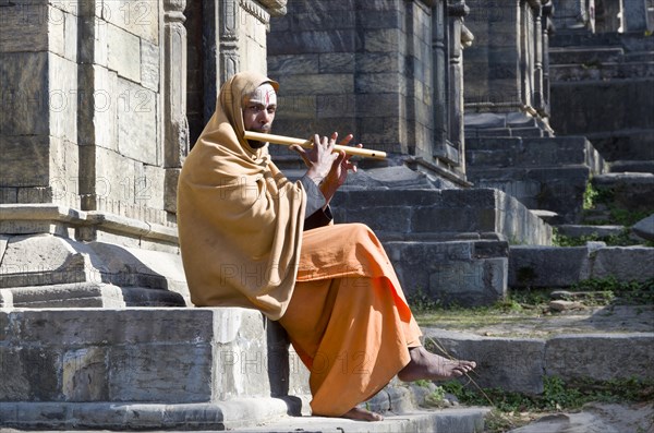 Young man playing flute at the burning ghats