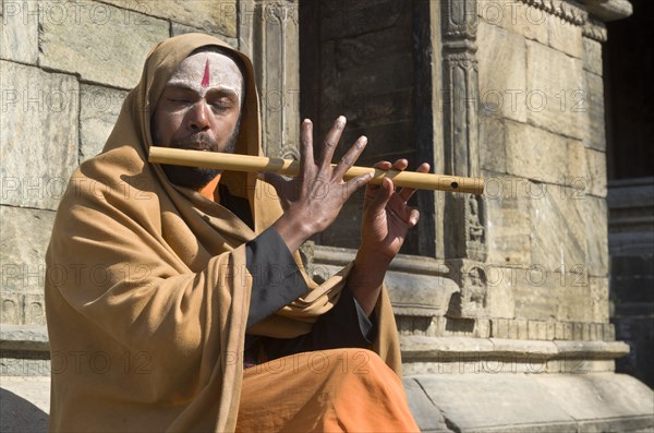 Young man playing flute at the burning ghats