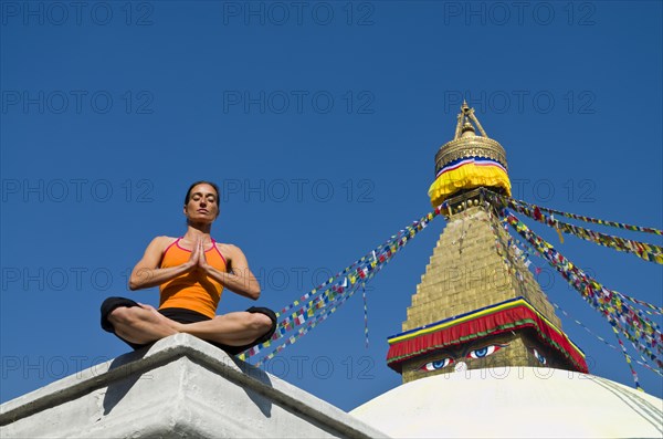 Young woman practicing yoga at Boudnanath stupa