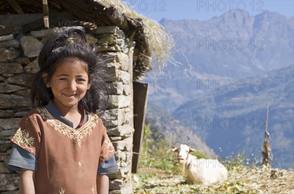 Portrait of a local girl with house and goat in the back