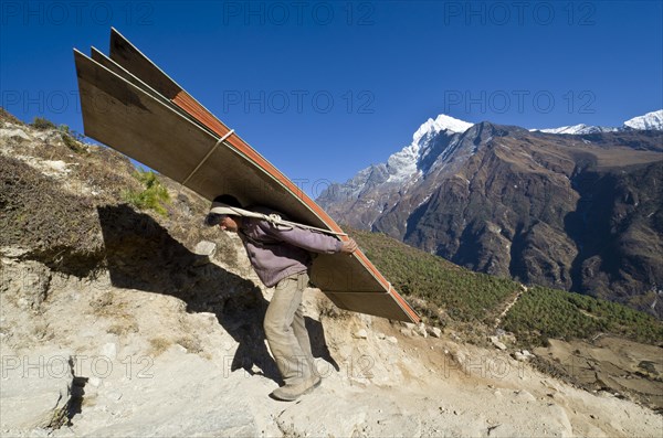 Porter carrying heavy load up an ascending track above Namche Bazar (3.440 m)