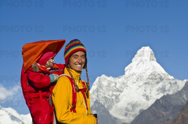 Young tourist mother carrying her little child in a rack on her back