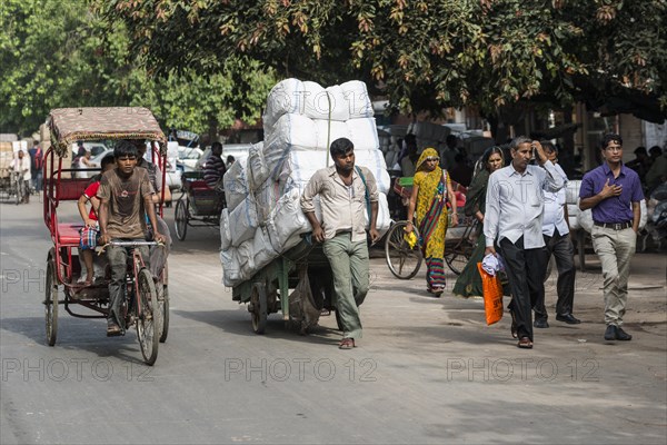 A cycle rickshaw and a man transporting goods on a hand cart on Khari Baoli Road