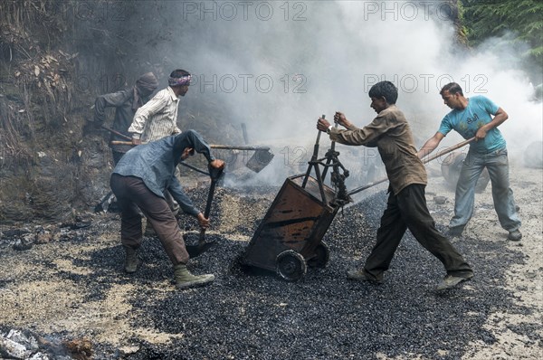 Workers applying hot asphalt to a road at a construction site