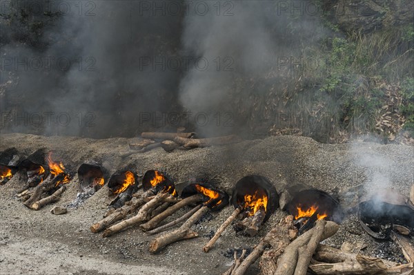 Gravel and hot tar being mixed on open fires at a road construction site