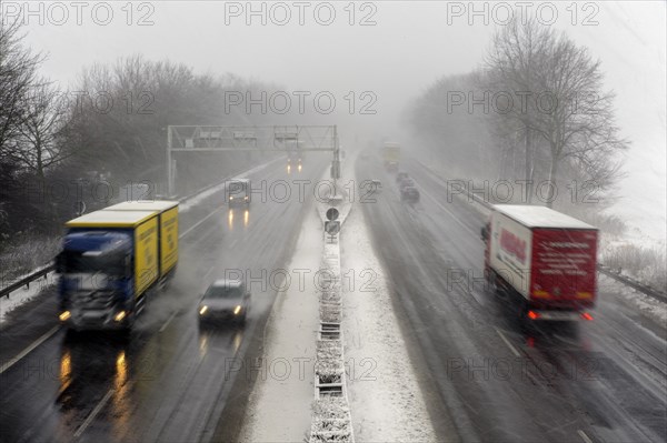 Trucks and cars on a motorway with heavy snowfall and poor visibility