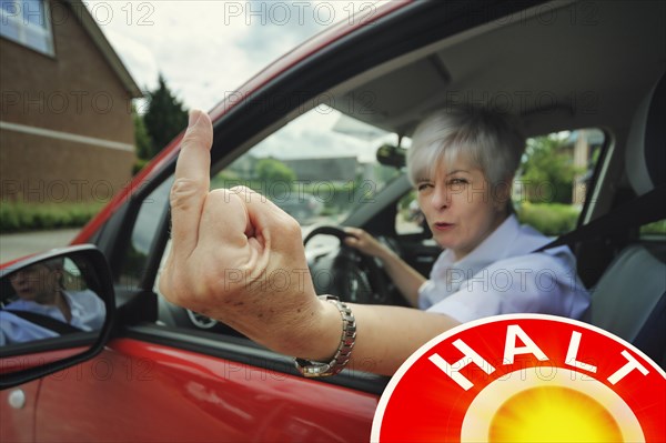 Woman car driver making a rude hand gesture during a traffic control