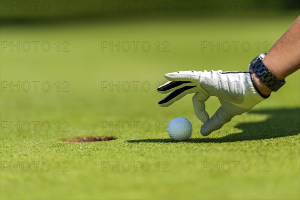 Finger flicking the golf ball into the hole