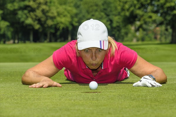 Female golfer blowing a golf ball into the hole