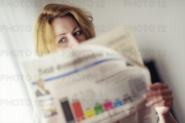 Young woman reading a newspaper with the prognosis of the German federal election