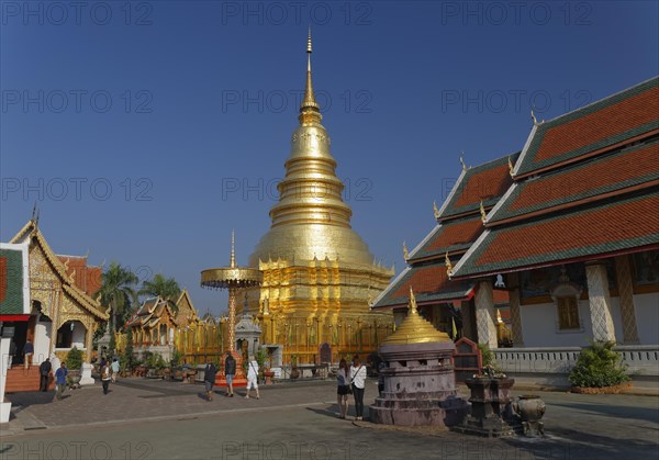 Golden chedi or pagoda with a ceremonial umbrella in the temple complex of Wat Phrathat Hariphunchai Woramahaviharn