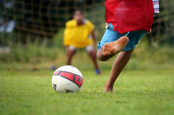 Barefoot boy taking a penalty kick