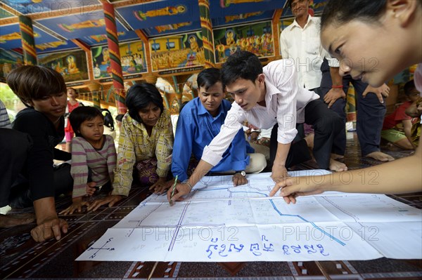 Men and women from the village discussing with representatives of a charity organization