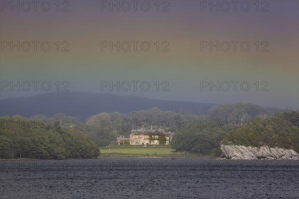 Muckross House on Muckross Lake with rainbow colors in the sky