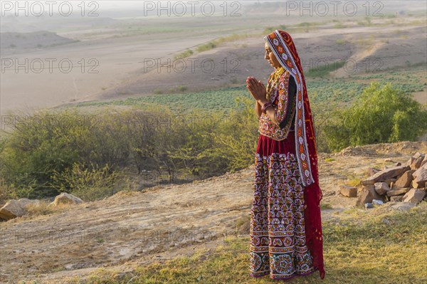 Ahir woman in traditional colorful clothes meditating at sunset